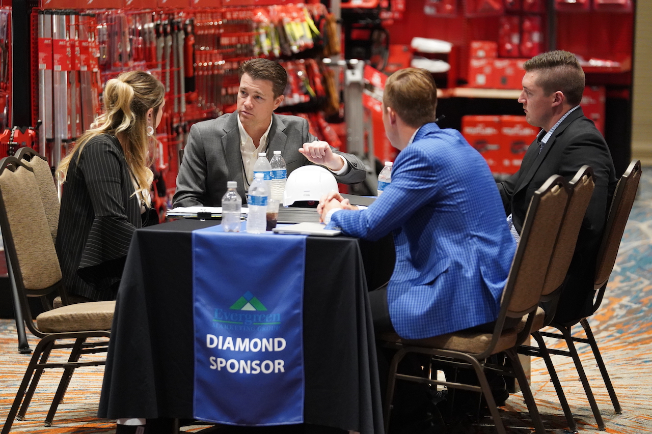 One woman and three men sit at a conference table